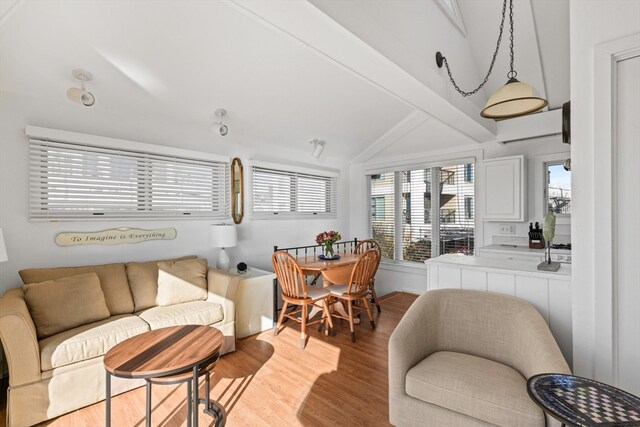 living room featuring lofted ceiling with beams, light hardwood / wood-style floors, and a wall mounted air conditioner