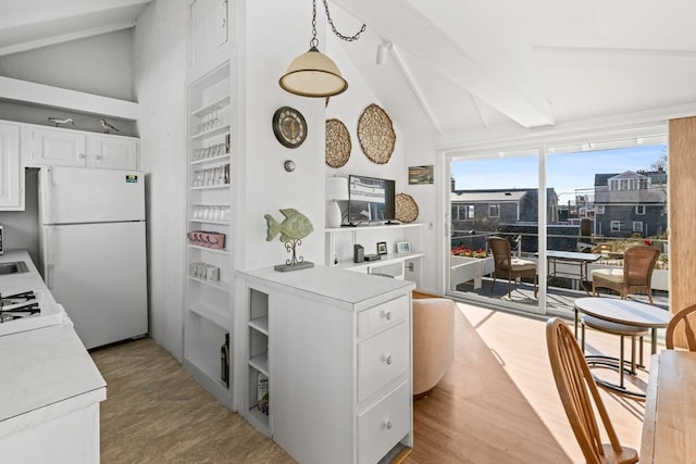 kitchen featuring light hardwood / wood-style floors, pendant lighting, vaulted ceiling with beams, white fridge, and white cabinetry