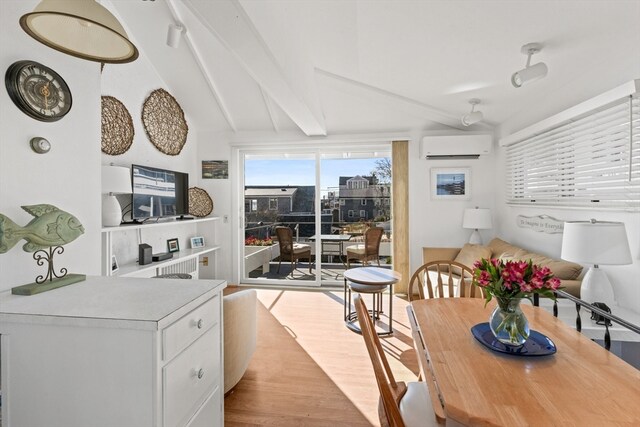 dining room featuring an AC wall unit, vaulted ceiling with beams, and light hardwood / wood-style flooring