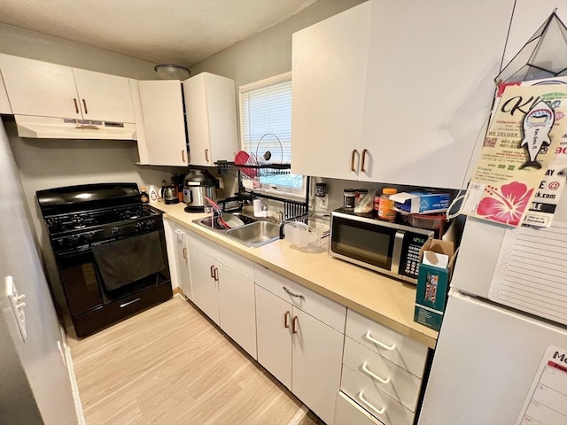 kitchen with black gas range, sink, white fridge, light hardwood / wood-style floors, and white cabinets