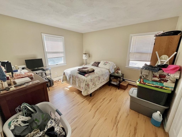 bedroom featuring a textured ceiling, light hardwood / wood-style floors, and a baseboard radiator