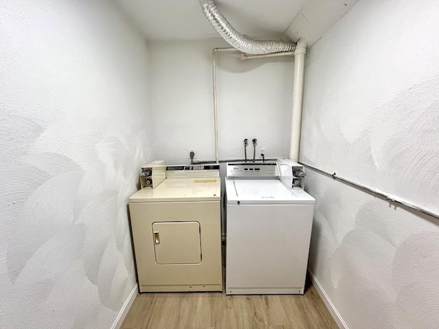 clothes washing area with independent washer and dryer and light hardwood / wood-style flooring