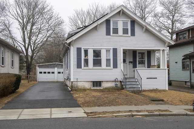 bungalow-style house with covered porch, a detached garage, and an outbuilding