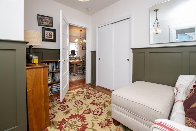 bedroom featuring a closet, a decorative wall, wainscoting, wood finished floors, and a chandelier