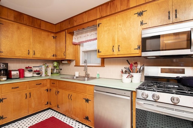 kitchen featuring light floors, stainless steel appliances, a sink, and light countertops