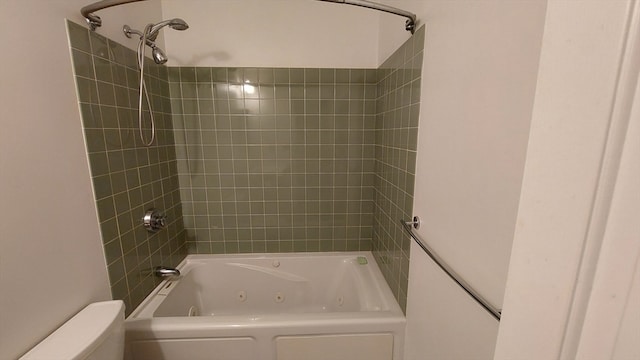 bathroom with tiled shower / bath combo and toilet