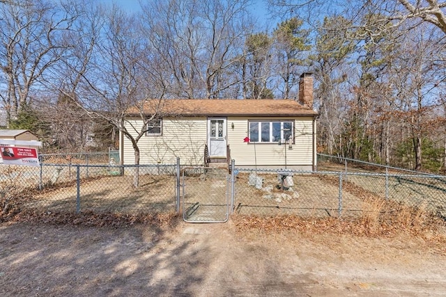 view of front facade with a fenced front yard, entry steps, a chimney, and a gate