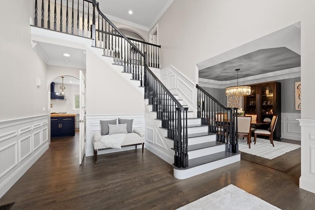 19 Cardiff Rd, Windham, NH 03087 - stairway with ornamental molding, a chandelier, arched walkways, a decorative wall, and wood finished floors