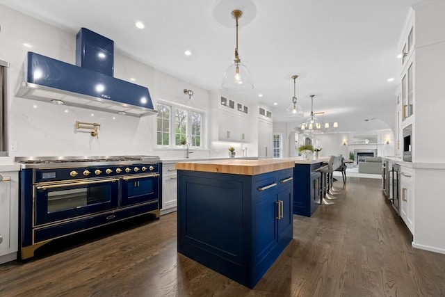 19 Cardiff Rd, Windham, NH 03087 - kitchen with butcher block counters, blue cabinets, wall chimney range hood, range with two ovens, and a kitchen island