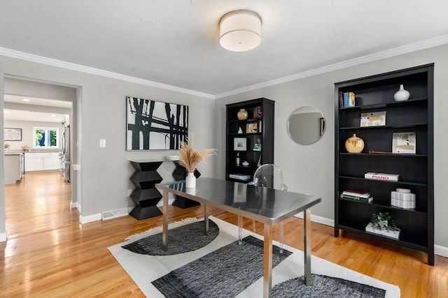 office featuring light wood-style flooring, crown molding, and baseboards