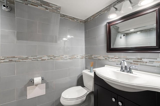 bathroom featuring tile walls, toilet, vanity, and backsplash