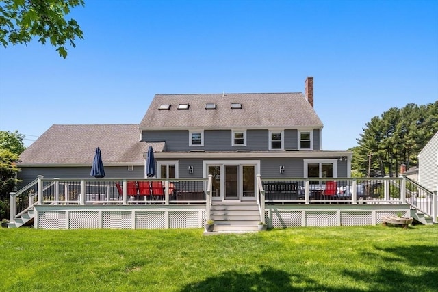 rear view of property with a chimney, a yard, and a deck