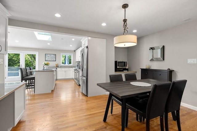 dining space with a skylight, light wood-style floors, and recessed lighting