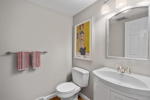 half bathroom featuring toilet, vanity, and baseboards