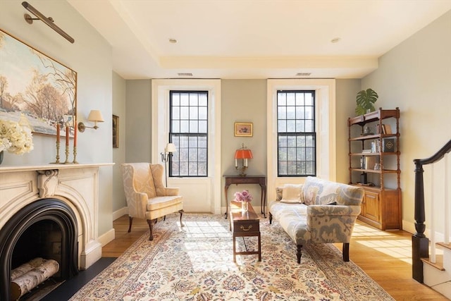 living area featuring light wood-style floors, visible vents, baseboards, and a fireplace