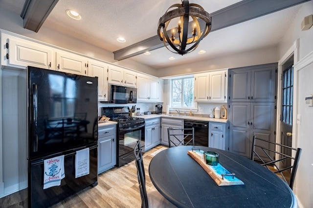 kitchen featuring black appliances, sink, white cabinets, and beamed ceiling