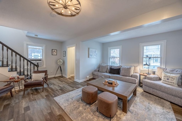 living room with cooling unit, an inviting chandelier, wood-type flooring, and a baseboard heating unit