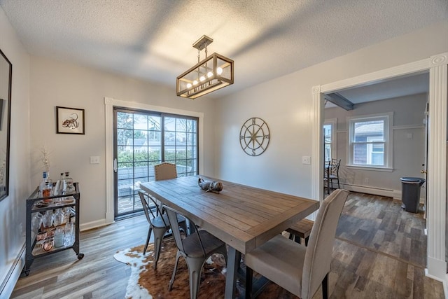 dining area with a healthy amount of sunlight, a baseboard radiator, and a textured ceiling