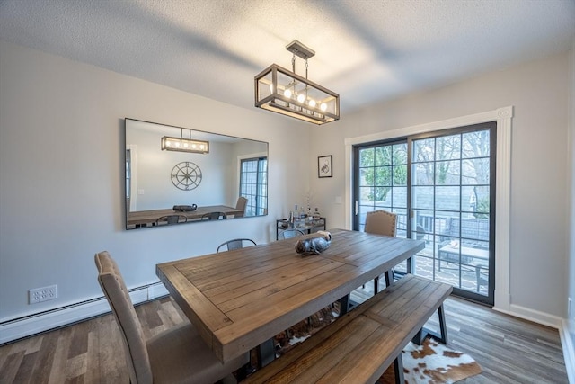 dining room with a chandelier, a textured ceiling, hardwood / wood-style flooring, and baseboard heating