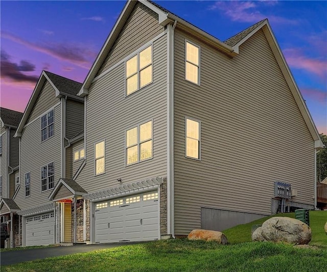 property exterior at dusk featuring a garage and a lawn