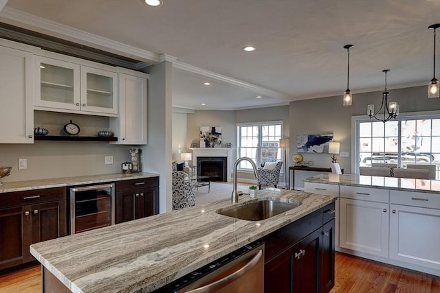 kitchen featuring sink, wine cooler, ornamental molding, an island with sink, and white cabinets