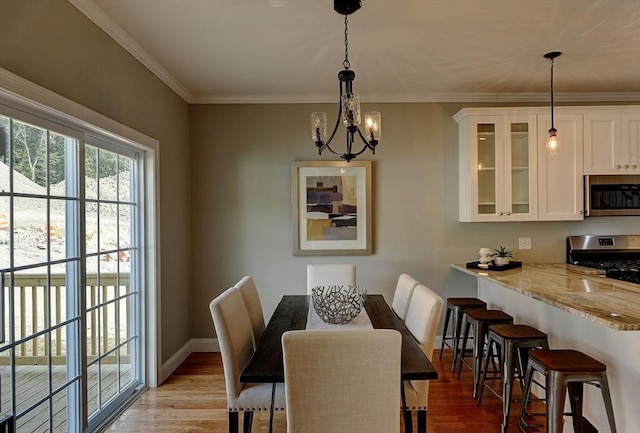 dining area with crown molding, a chandelier, and light wood-type flooring