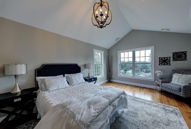 bedroom with hardwood / wood-style flooring, lofted ceiling, and a chandelier