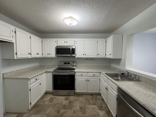 kitchen featuring stainless steel appliances, white cabinetry, sink, and a textured ceiling