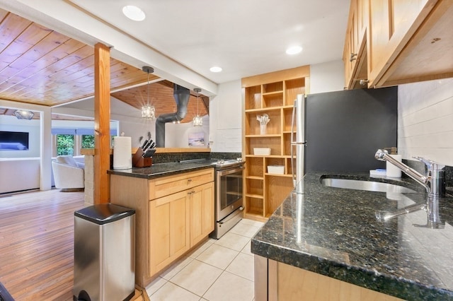 kitchen with light wood-type flooring, appliances with stainless steel finishes, sink, and dark stone counters