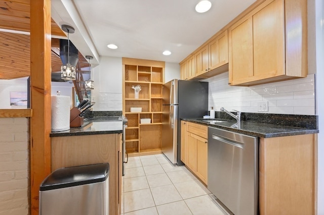 kitchen with dark stone countertops, sink, light tile patterned floors, and appliances with stainless steel finishes