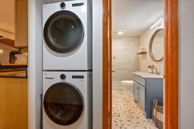 clothes washing area with stacked washer and clothes dryer and sink