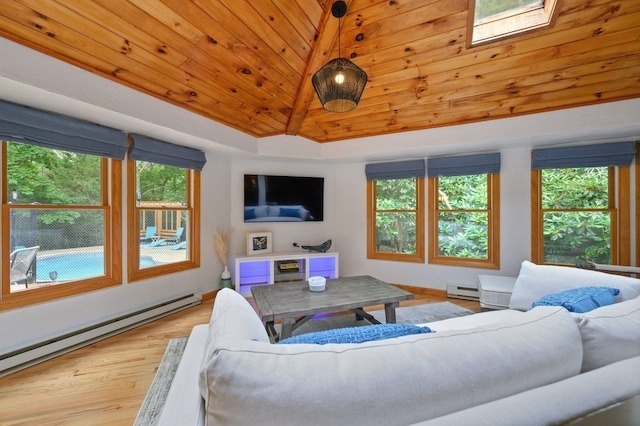 living room featuring baseboard heating, plenty of natural light, vaulted ceiling with skylight, and wood-type flooring