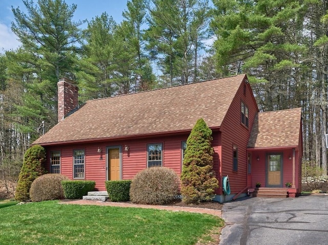 chalet / cabin with a chimney, roof with shingles, and a front lawn