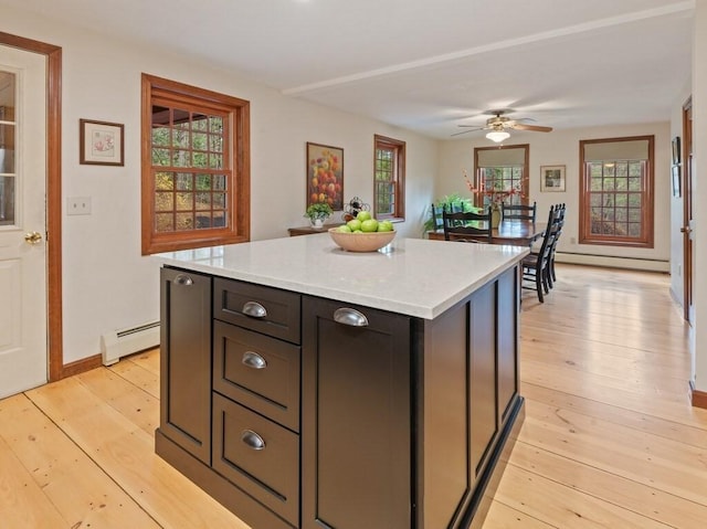 kitchen with a center island, a baseboard radiator, light wood finished floors, and light countertops