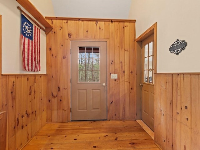 doorway to outside with wood walls, light wood-type flooring, and a wainscoted wall
