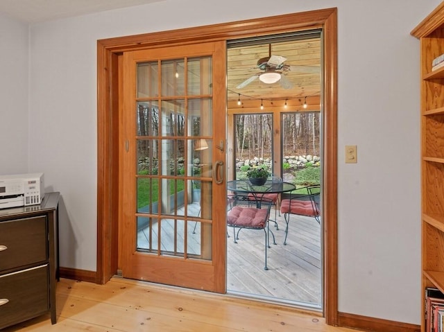 doorway featuring baseboards, ceiling fan, and light wood-style flooring