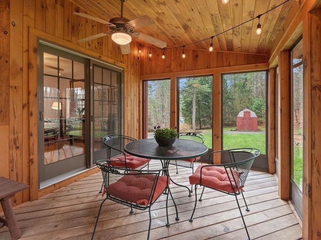 sunroom with a ceiling fan, rail lighting, and outdoor dining space