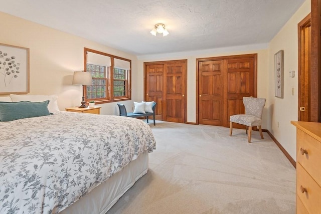 bedroom featuring multiple closets, baseboards, and light colored carpet