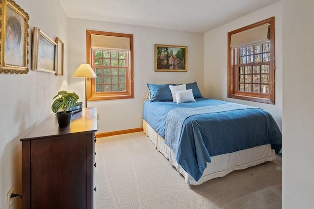 bedroom with baseboards, light carpet, and multiple windows