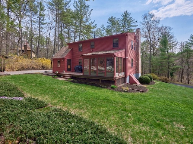 back of property with a yard, a wooden deck, and a chimney