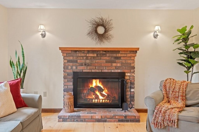 details featuring a brick fireplace, baseboards, and wood finished floors