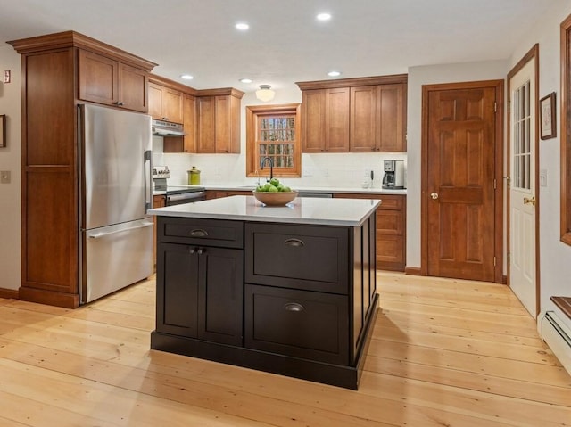 kitchen featuring appliances with stainless steel finishes, brown cabinets, a sink, light countertops, and under cabinet range hood