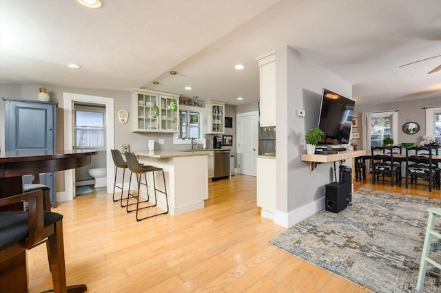 kitchen featuring kitchen peninsula, white cabinetry, a breakfast bar, and plenty of natural light