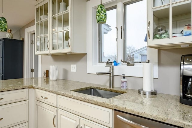 kitchen featuring stainless steel dishwasher, plenty of natural light, light stone counters, and sink