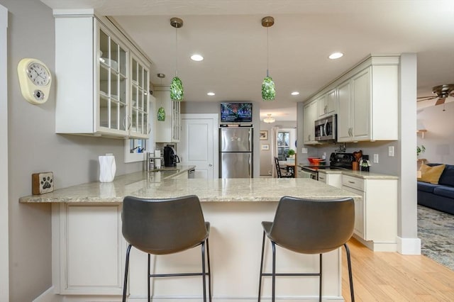 kitchen with kitchen peninsula, pendant lighting, a breakfast bar, and stainless steel appliances