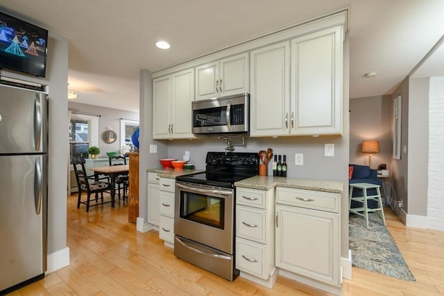 kitchen featuring light stone counters, light wood-type flooring, and appliances with stainless steel finishes