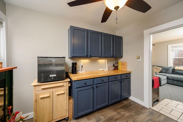 kitchen featuring blue cabinetry, dark hardwood / wood-style floors, ceiling fan, and butcher block counters