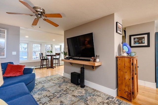 living room with ceiling fan, light wood-type flooring, and baseboard heating