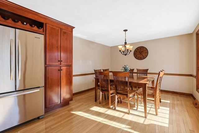 dining room with light wood-style flooring, baseboards, and a notable chandelier