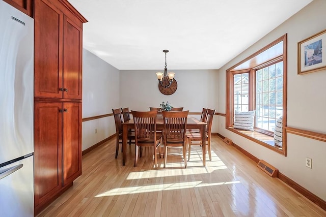 dining space with a notable chandelier, light wood-style flooring, visible vents, and baseboards